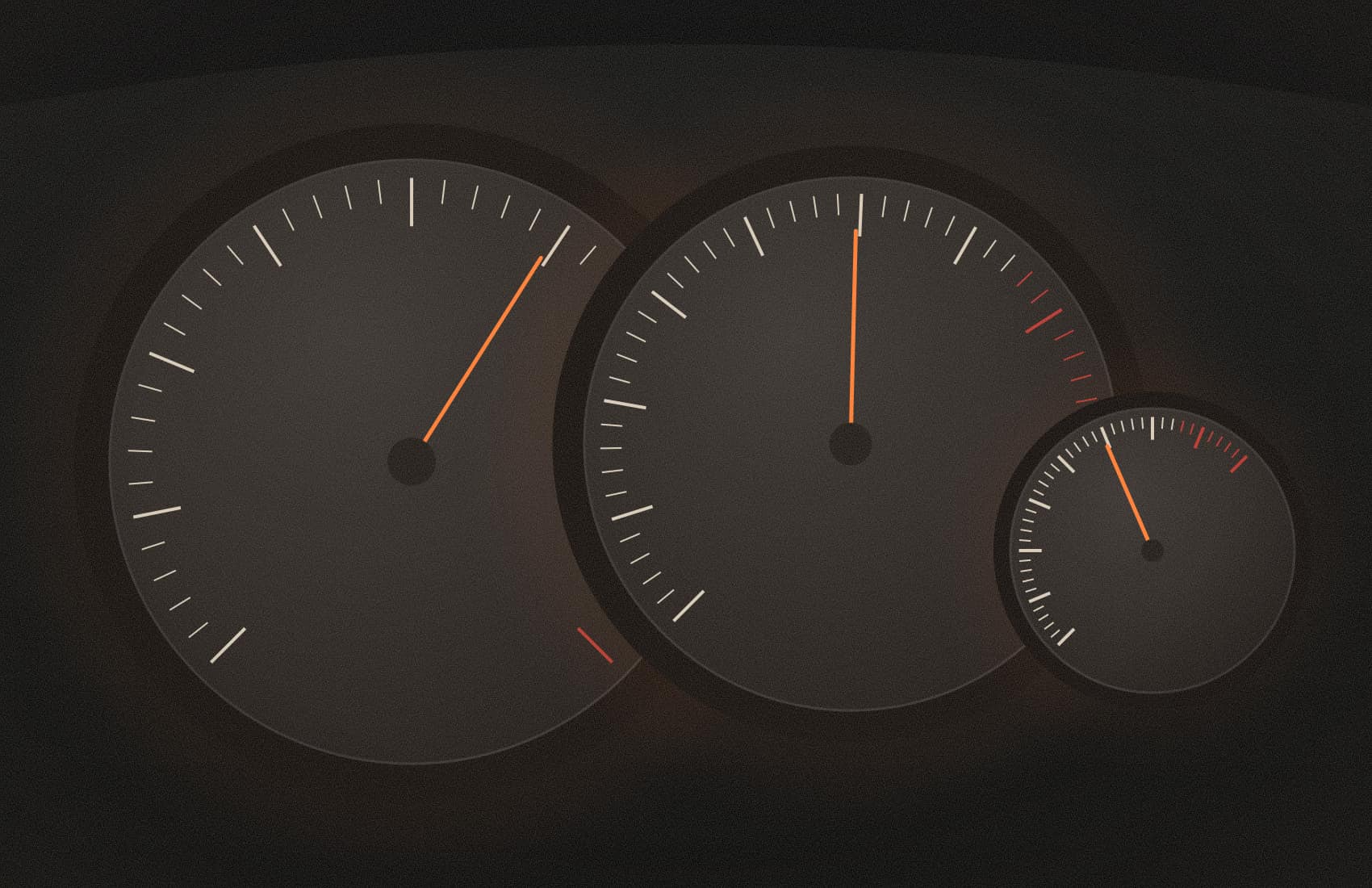 Three round instrument gauges with orange needles